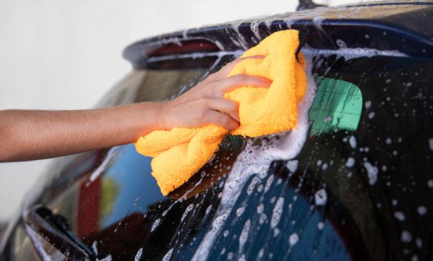 a man cleaning car window with soap and water