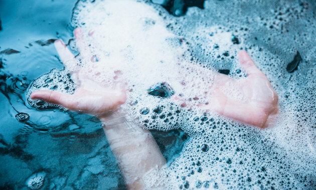 a man is dipping his hand in cold soapy water 