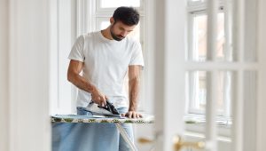 a man is ironing his blue dress shirt