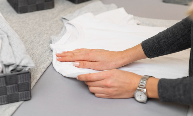 a woman is pressing a white shirt with her hands placed over a hard board