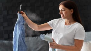 a girl is using a steaming iron to steam iron clothes