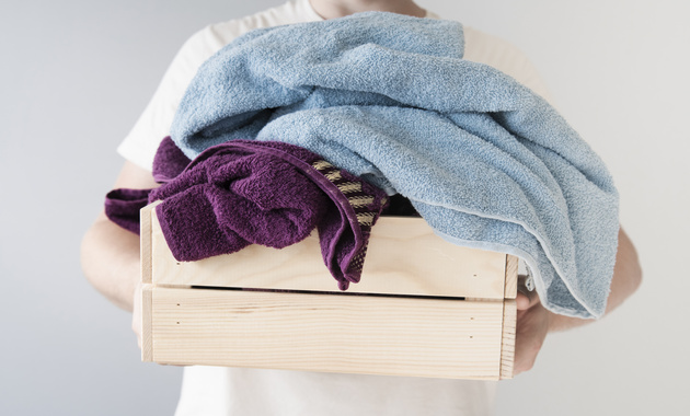 a man holding laundry basket full of towels